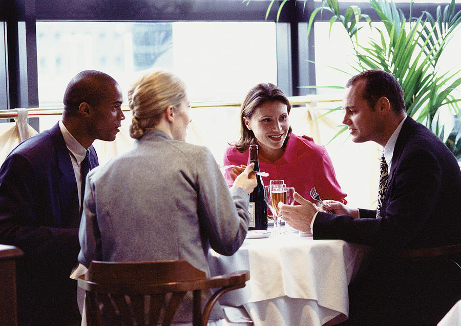 Group of business people sitting at table, eating Photograph by Teo Lannie