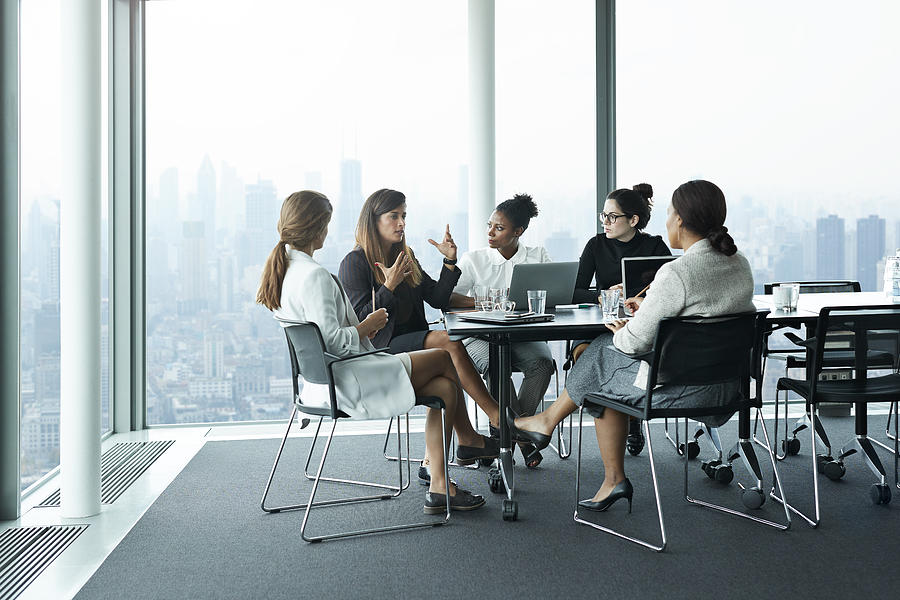 Group of businesswomen having meeting in boardroom with stunning skyline view Photograph by Klaus Vedfelt