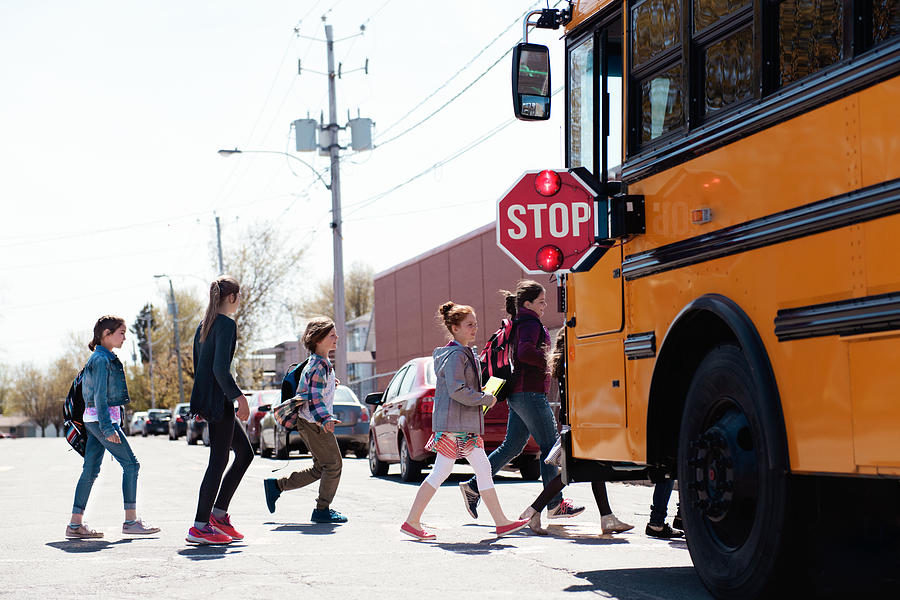 Group of elementary school kids getting in a school bus at schools out. Photograph by Manonallard