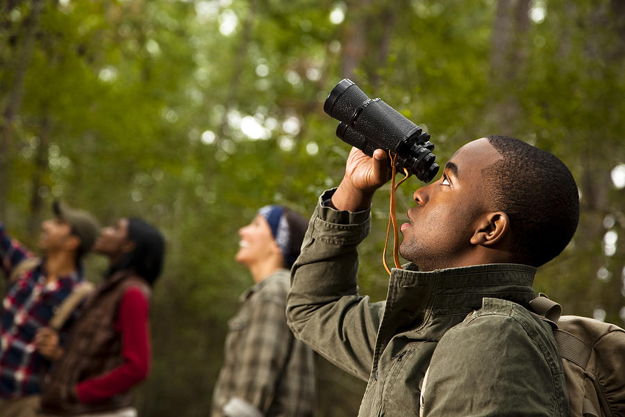 Group of friends camping and hiking using binoculars. Bird watching. Photograph by Fstop123
