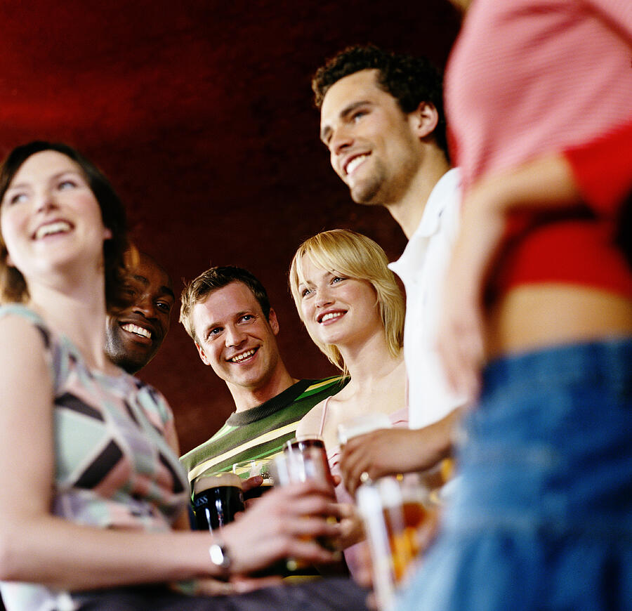 Group of friends in pub holding drinks, smiling, low angle view Photograph by Digital Vision