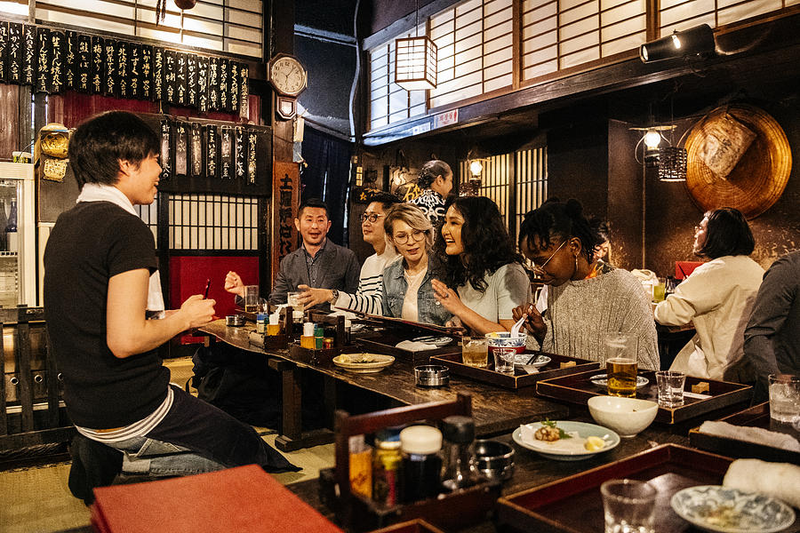 Group of friends ordering food in Japanese Izakaya Photograph by JohnnyGreig