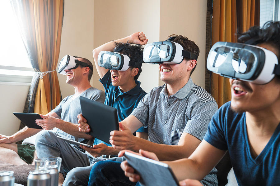 Group of friends playing games using virtual reality headsets Photograph by JGalione