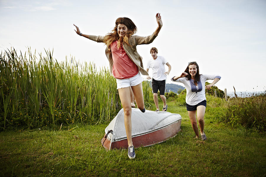 Group of friends running and jumping over boat Photograph by Thomas Barwick