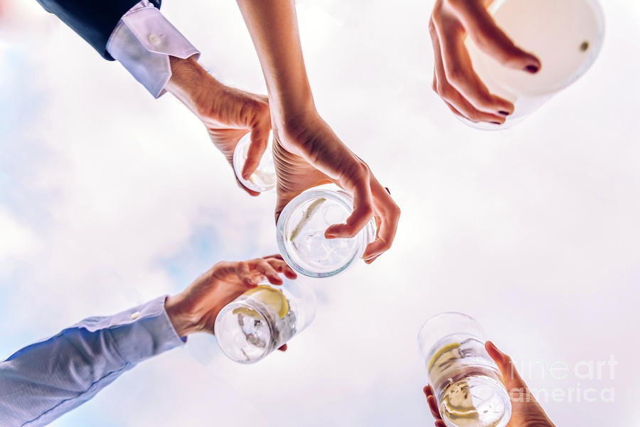 Group of friends toasting with a few glasses of alcohol with the sky in the background, seen from below. Photograph by Joaquin Corbalan