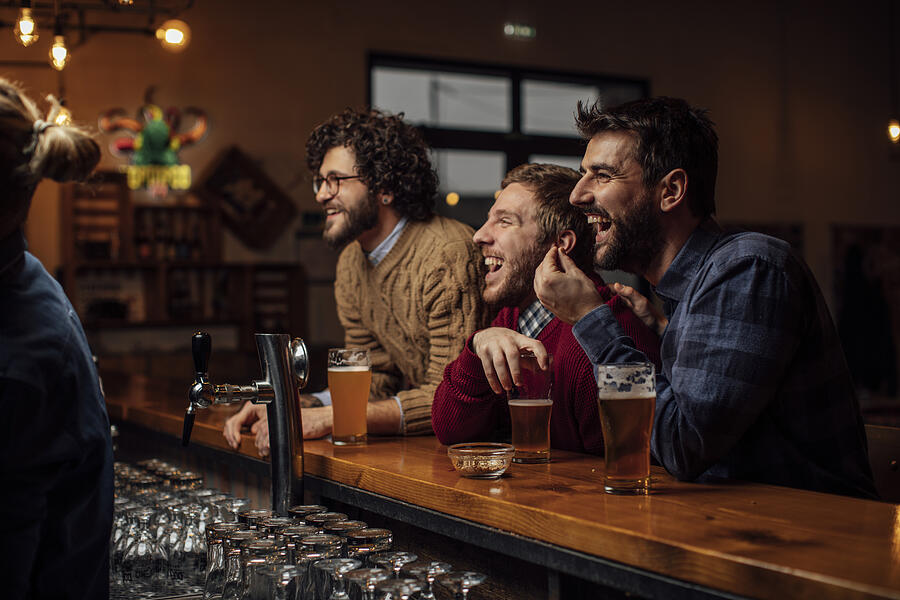 Group of Happy Young Men Drinking Beer and Watching a Soccer Game at the Pub Photograph by FreshSplash