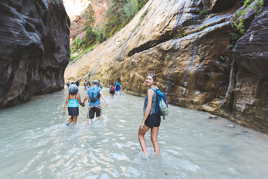 Group of hikers wade through water in a slot canyon Photograph by FatCamera