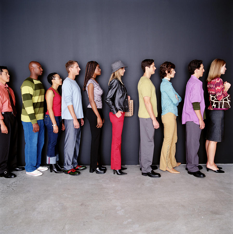Group of men and women waiting in line, side view Photograph by Ryan McVay