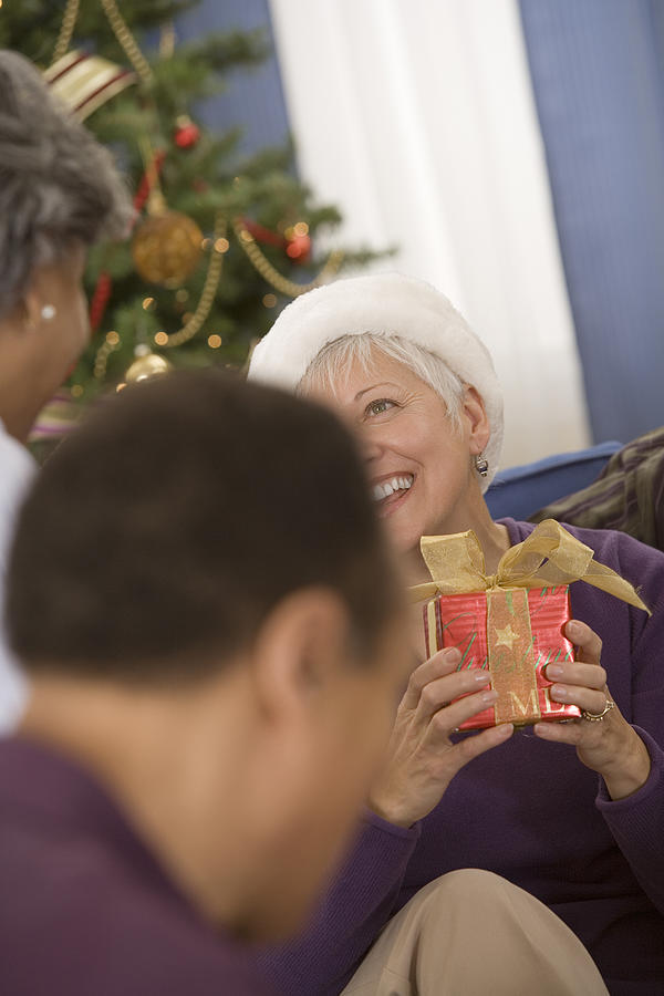 Group of people exchanging gifts at a christmas party Photograph by Comstock Images