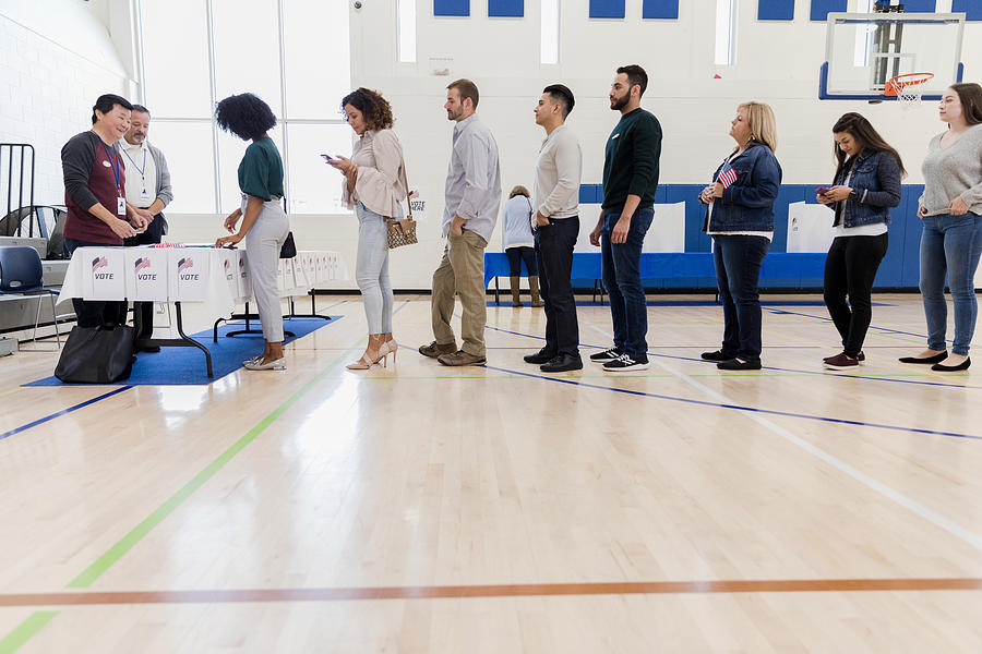 Group of people wait in long line in polling place Photograph by SDI Productions