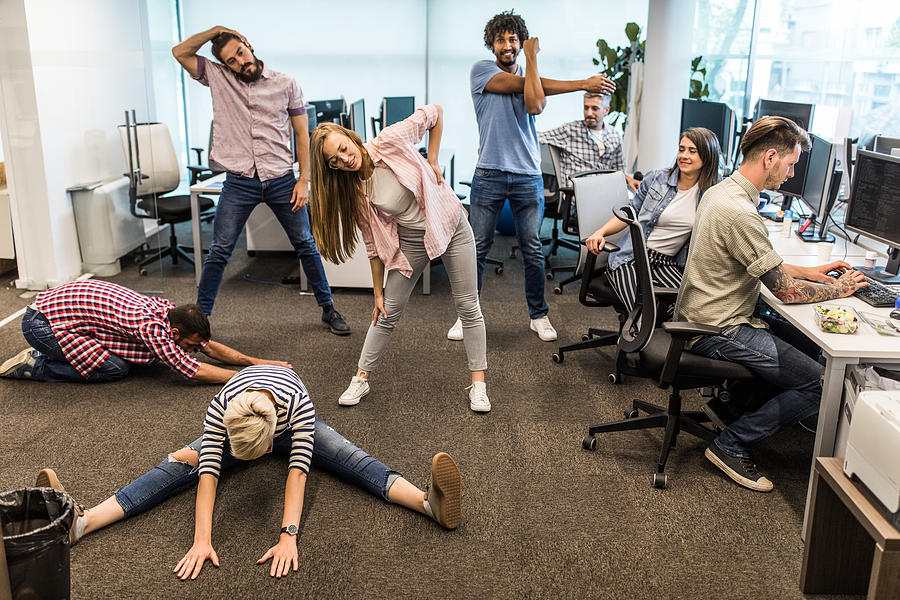 Group of programmers exercising on a break in the office. Photograph by Skynesher