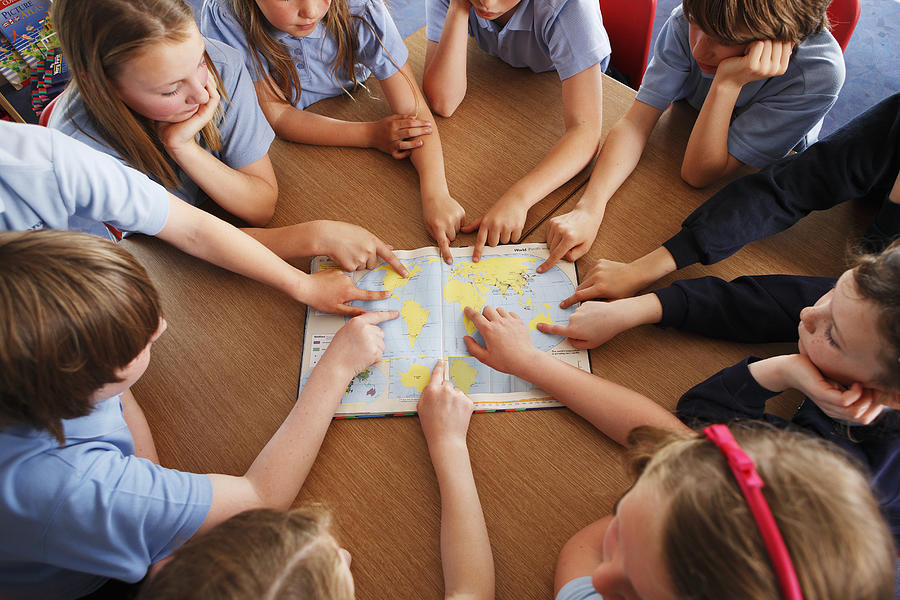 Group Of Schoolchildren Using Atlas Together Photograph by John Slater