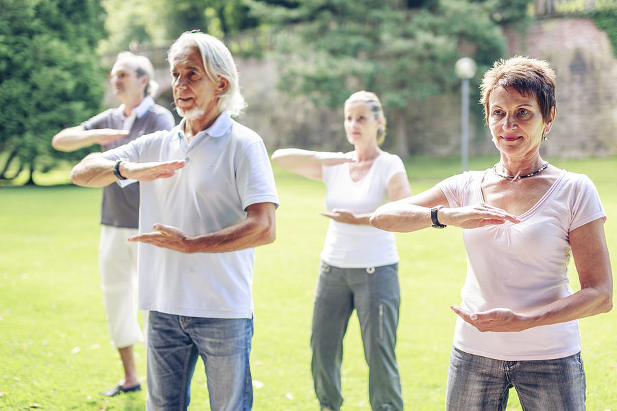 Group of seniors doing Tai chi in a park Photograph by Westend61