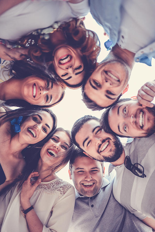 Group of Smiling Friends Creating Circle and Looking Down Photograph by AleksandarGeorgiev
