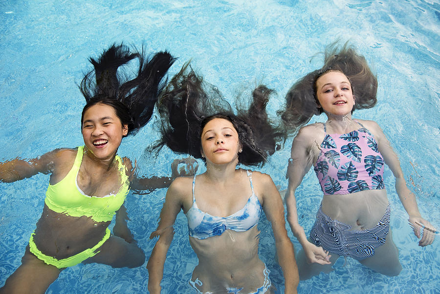 Group of teenage girls in pool playing mermaids. Photograph by Martinedoucet