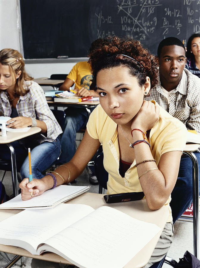 Group of Teenagers Sit at Desks in a Classroom Photograph by Digital Vision.
