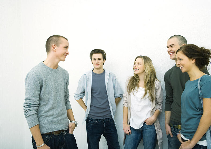 Group of young adult and teenage friends standing together, white background Photograph by PhotoAlto/Sigrid Olsson