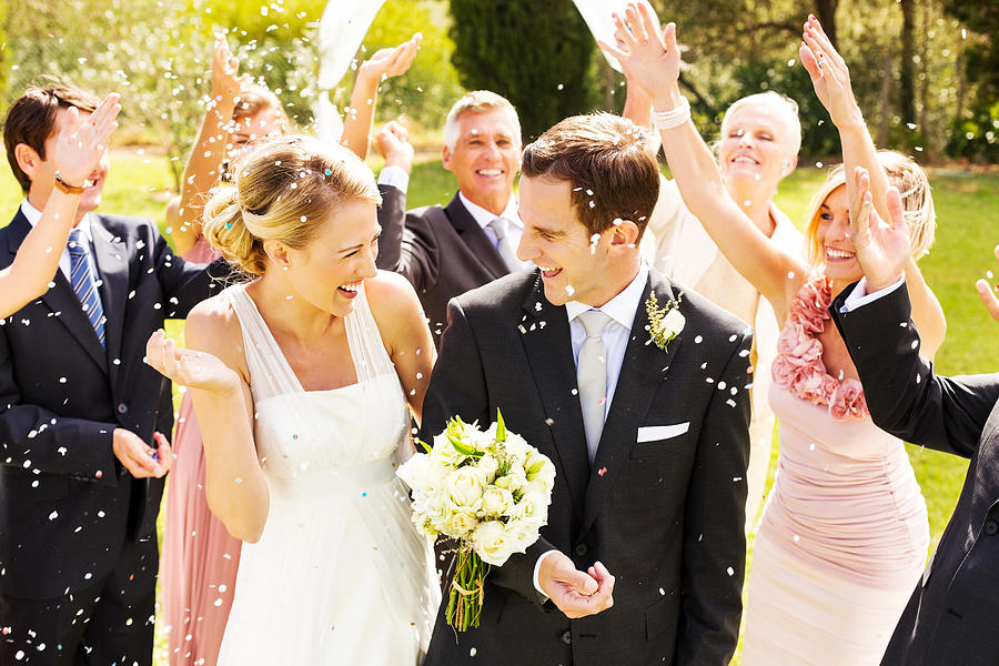 Guests Throwing Confetti On Couple During Reception In Garden Photograph by Neustockimages