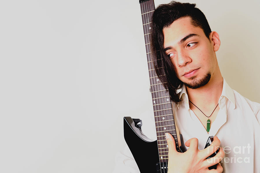 Guitarist posing with his electric guitar, white background. Photograph by Joaquin Corbalan