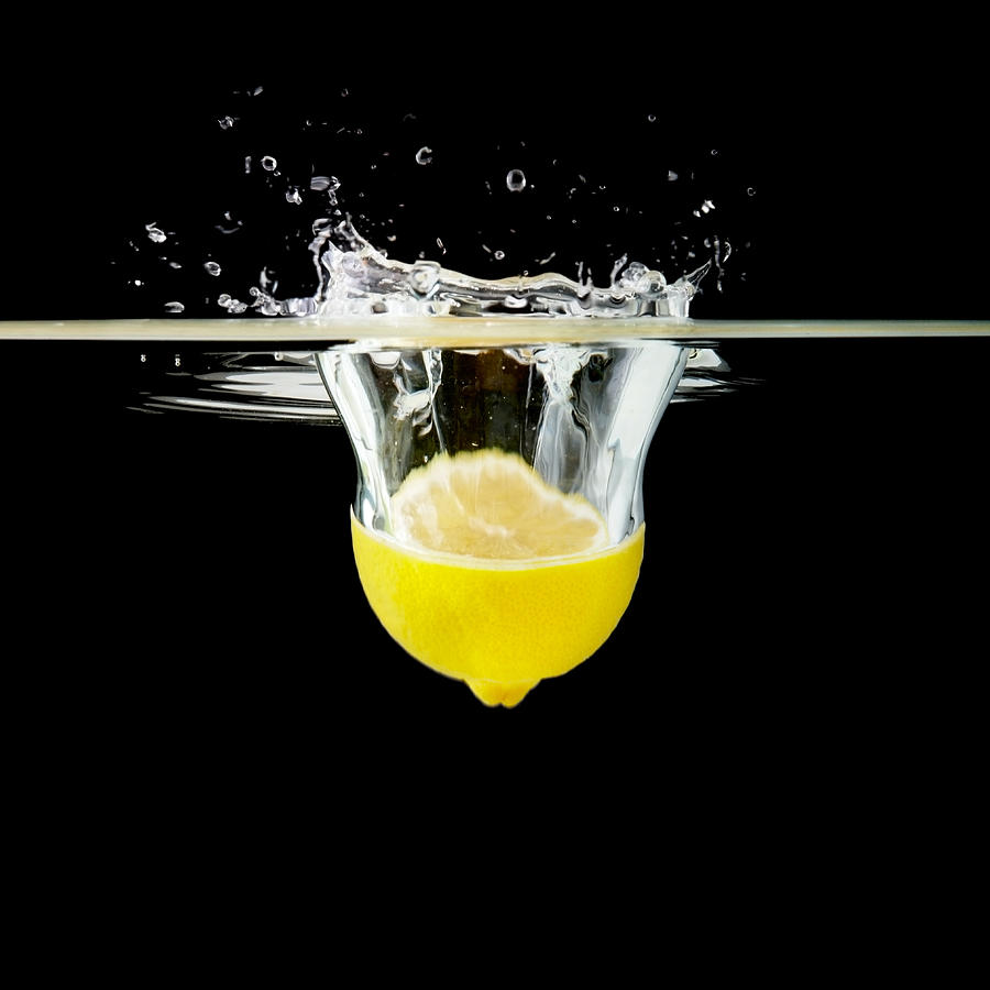 Half lemon falling into water Photograph by Urilux