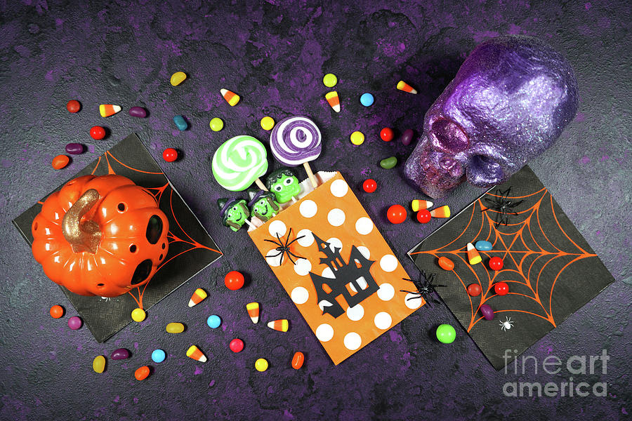 Halloween trick or treat flatlay on purple background with skull and pumpkin. Photograph by Milleflore Images