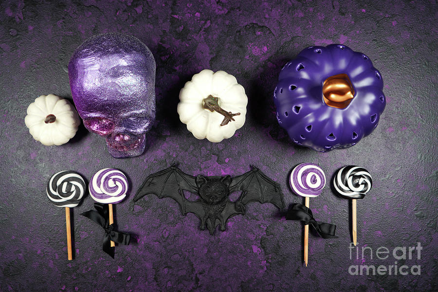 Halloween trick or treat flatlay on purple background with skull and pumpkins. Photograph by Milleflore Images