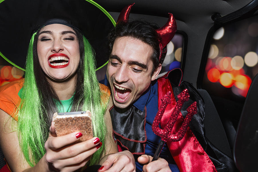 Halloween witch and devil laughing in back of car Photograph by Betsie Van Der Meer
