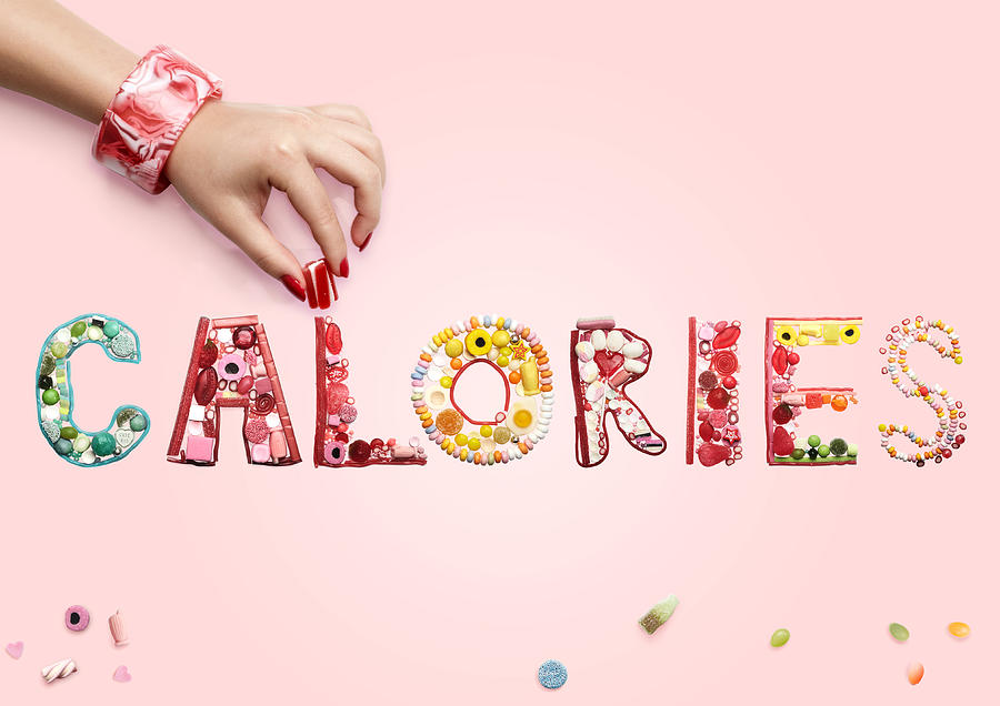Hand arranging sweets and candy spelling Calories Photograph by Paper Boat Creative