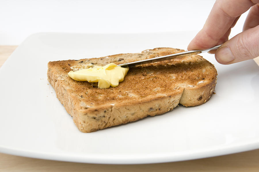 Hand buttering a piece of granary toast Photograph by Rachel Husband
