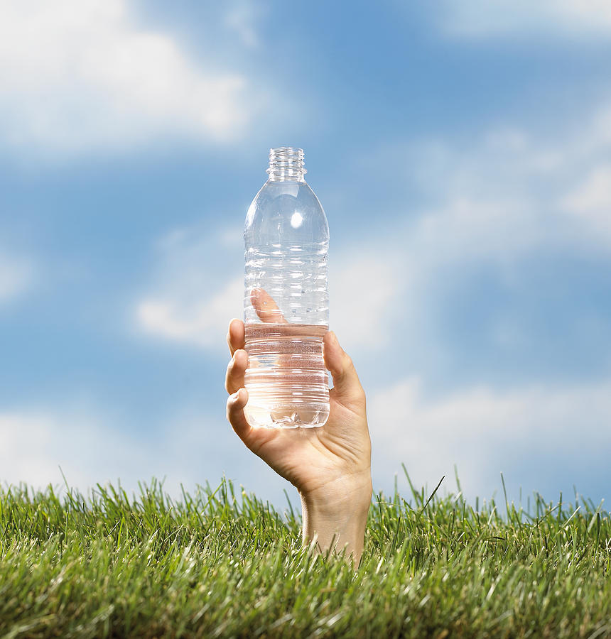 Hand coming out of grass holding water bottle. Photograph by Jim Esposito Photography L.L.C.