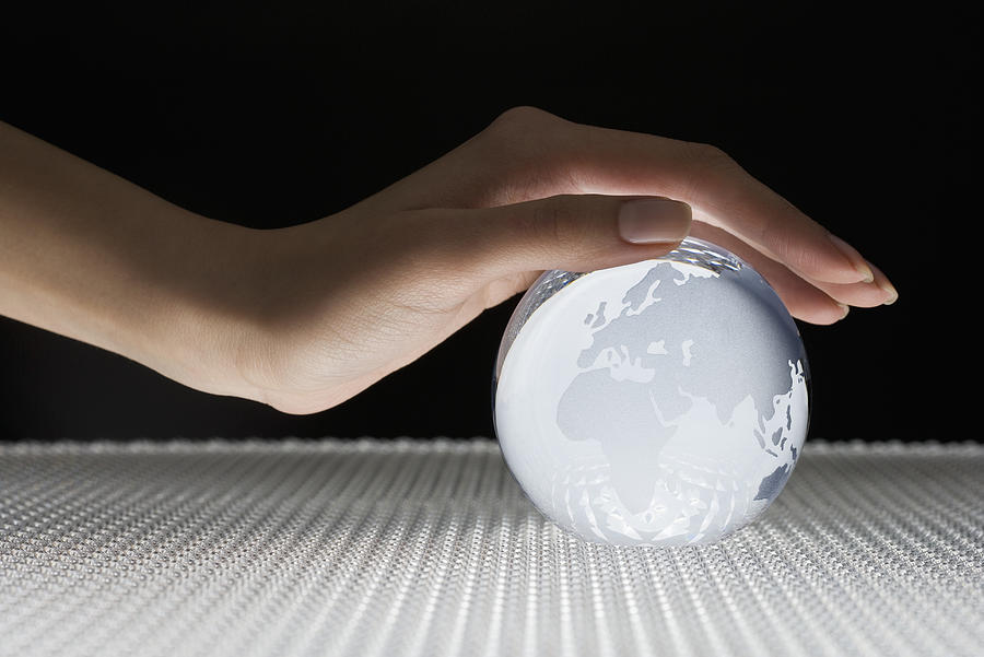 Hand Covering Glass Globe Photograph by Fuse