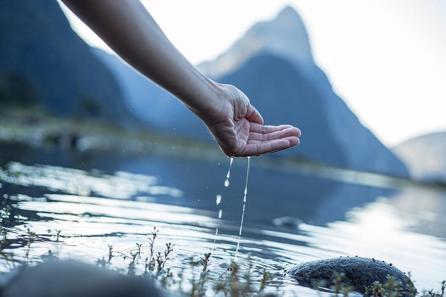 Hand cupped to catch fresh water from the lake-New Zealand Photograph by Swissmediavision