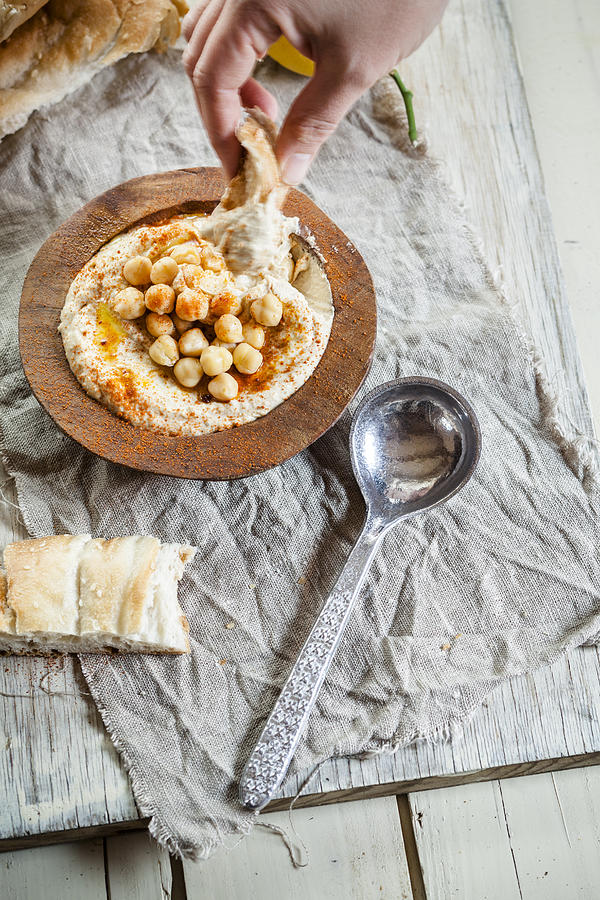 Hand dipping turkish flatbread into hummus Photograph by Westend61 Hand dipping turkish flatbread into hummus Photograph by Westend61