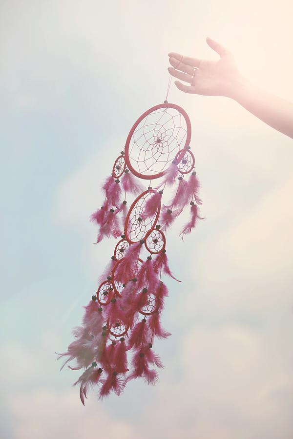 Hand holding a feathery dream catcher on blue sky Photograph by Susan.k.