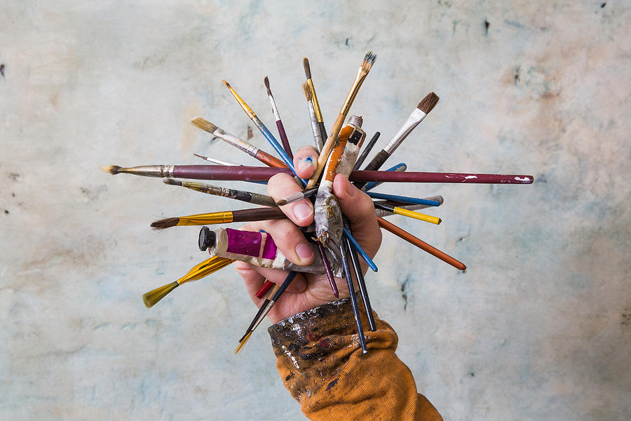 Hand holding cluster of paint brushes and paints Photograph by Dimitri Otis