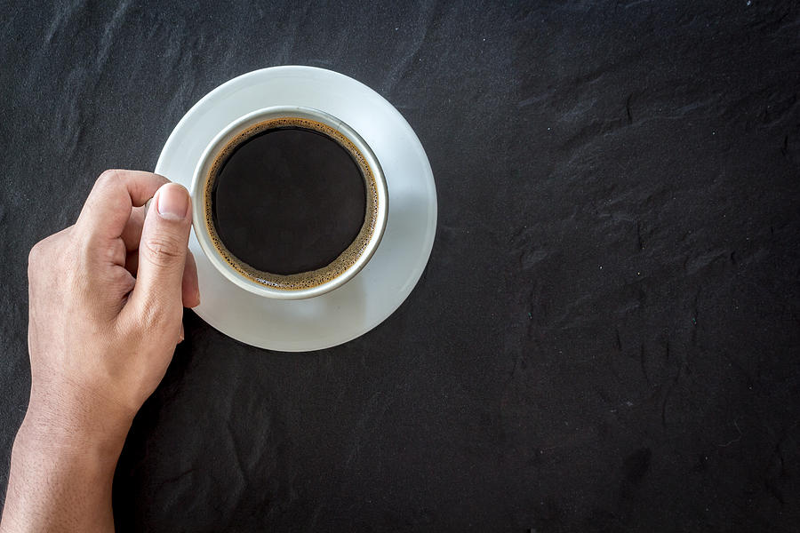 Hand holding cup of coffee  on black background Photograph by Arto_canon