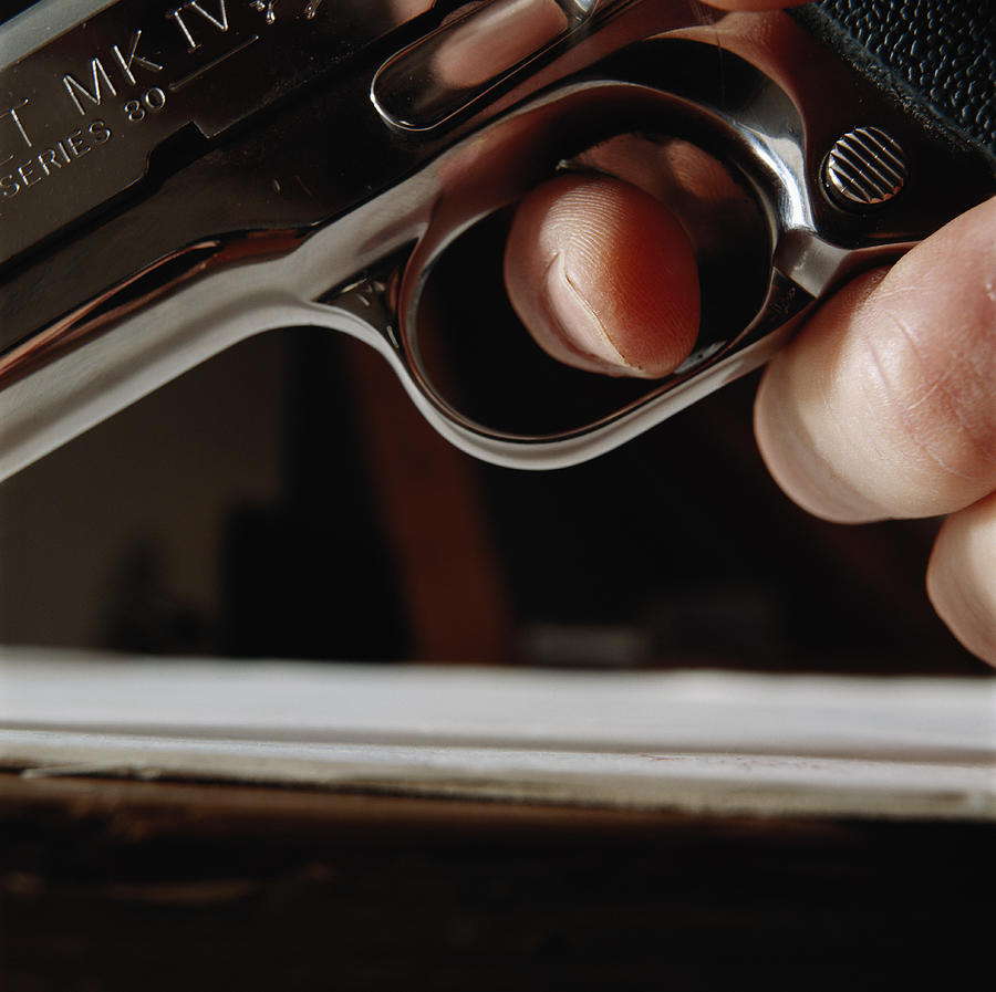 Hand holding gun, close-up, low angle view Photograph by David De Lossy