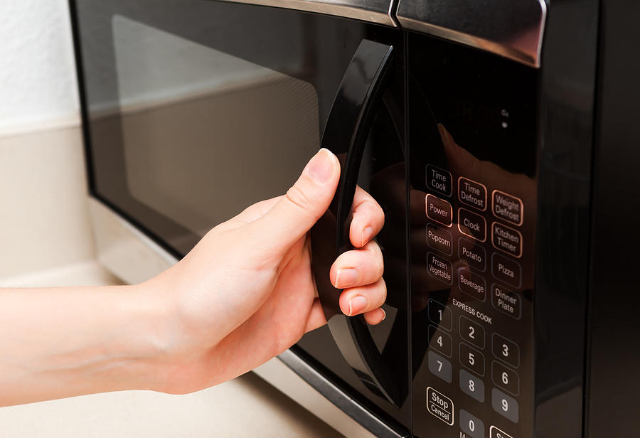 Hand holding microwave door close up Photograph by GetUpStudio