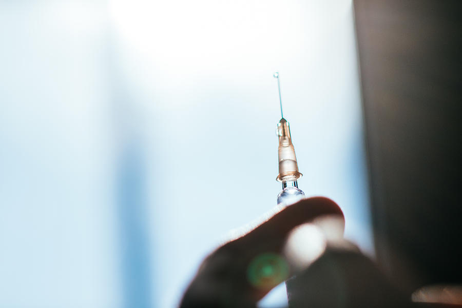 Hand holding syringe in backlight. Photograph by Guido Mieth