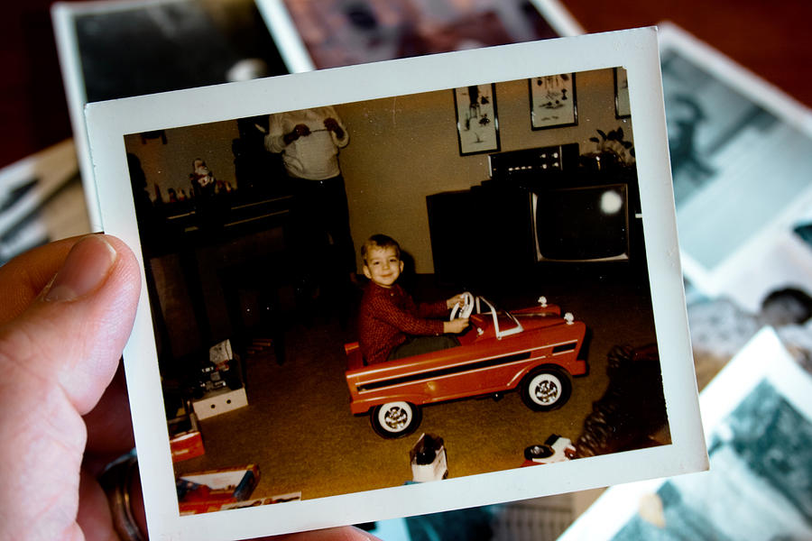 Hand holds Vintage photograph of boy in pedal car Photograph by Catscandotcom