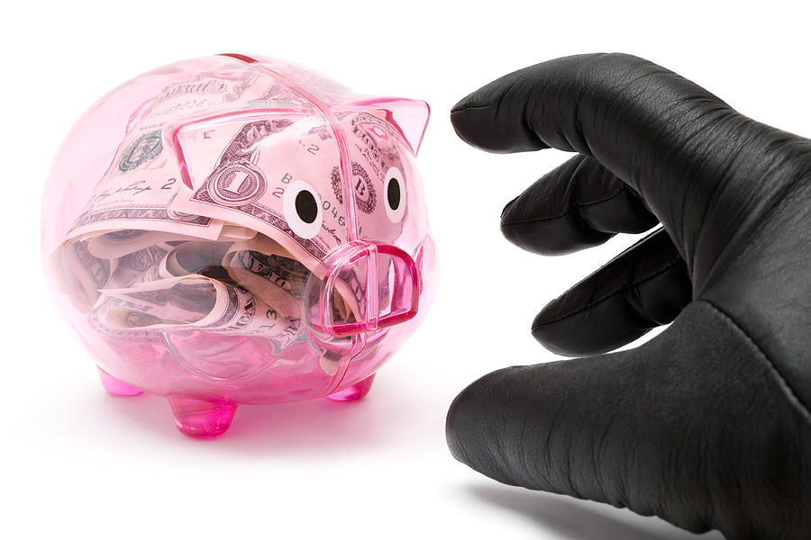 Hand in black glove reaching for a pink piggy bank Photograph by JoKMedia