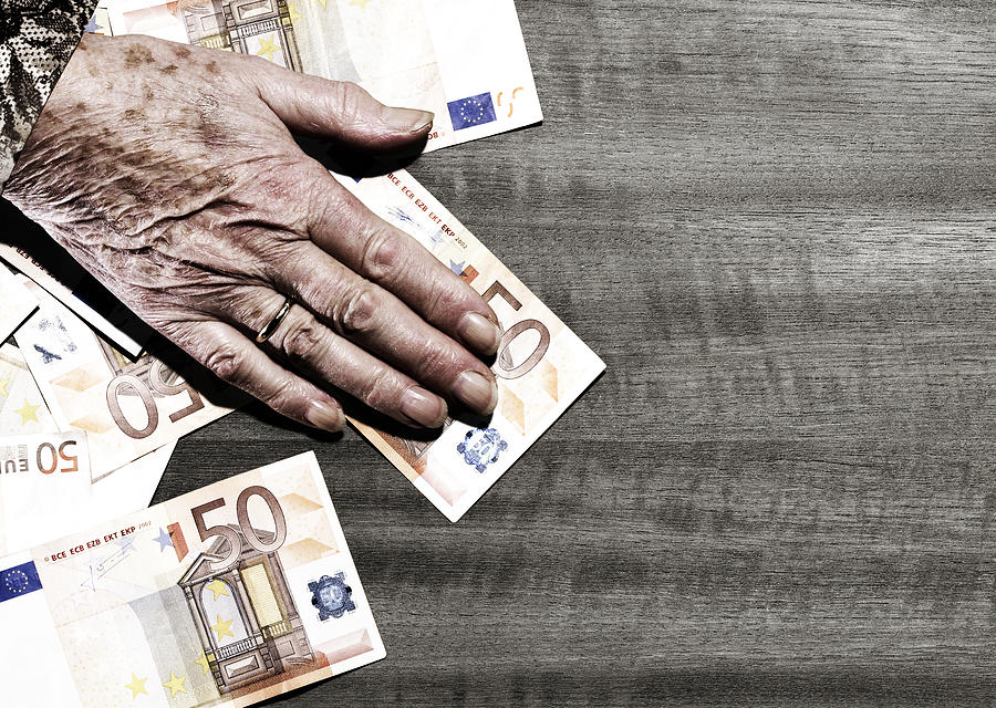 Hand of elderly woman on table with euro  Photograph by Maarten Wouters