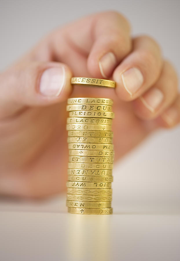 Hand putting a British Pound on a stack Photograph by Tom Grill