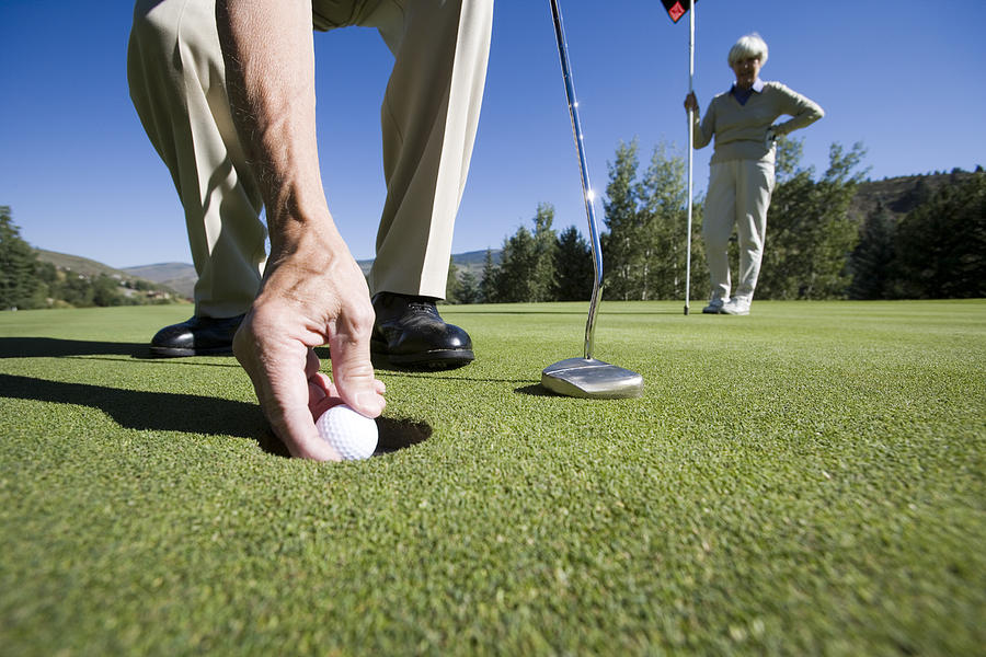 Hand putting golf ball on tee Photograph by Comstock Images