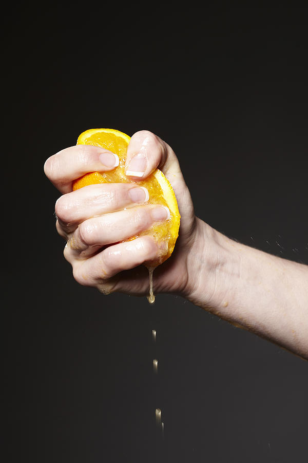 Hand squeezing orange Photograph by Liam Norris