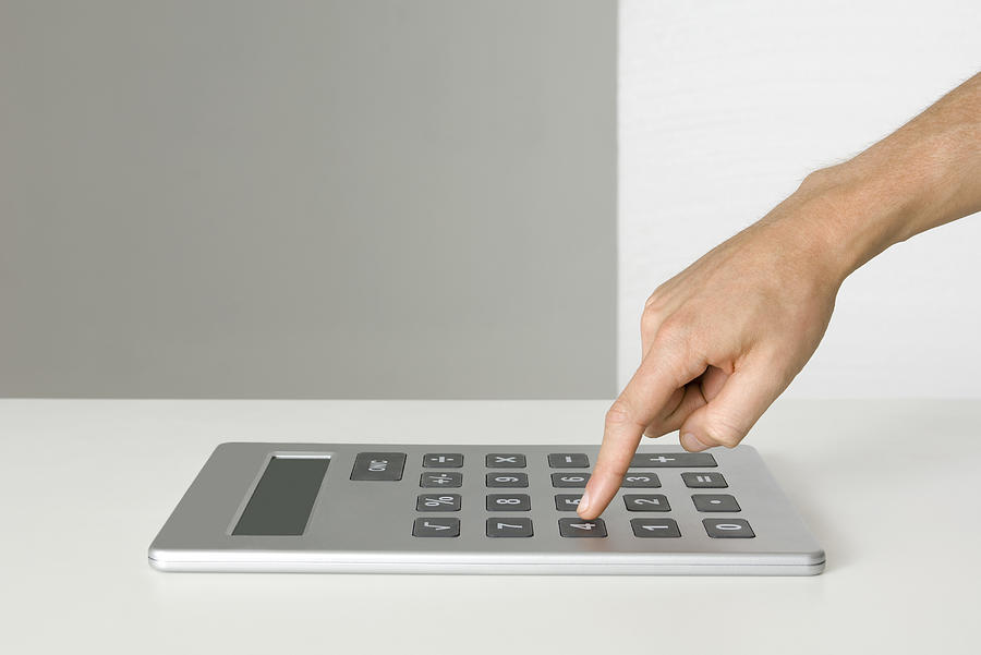 Hand using oversized calculator Photograph by PhotoAlto/Michele Constantini