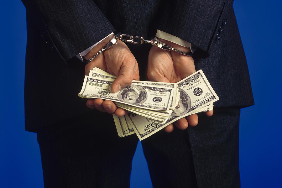 Handcuffed businessman holding cash Photograph by Comstock