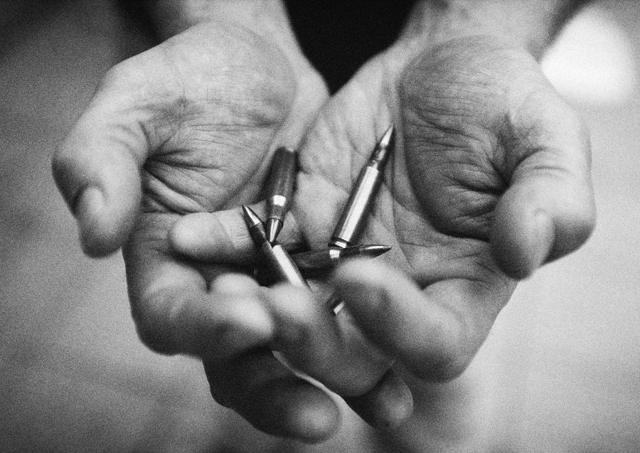 Hands holding bullets, close-up, b&w Photograph by Laurent Hamels
