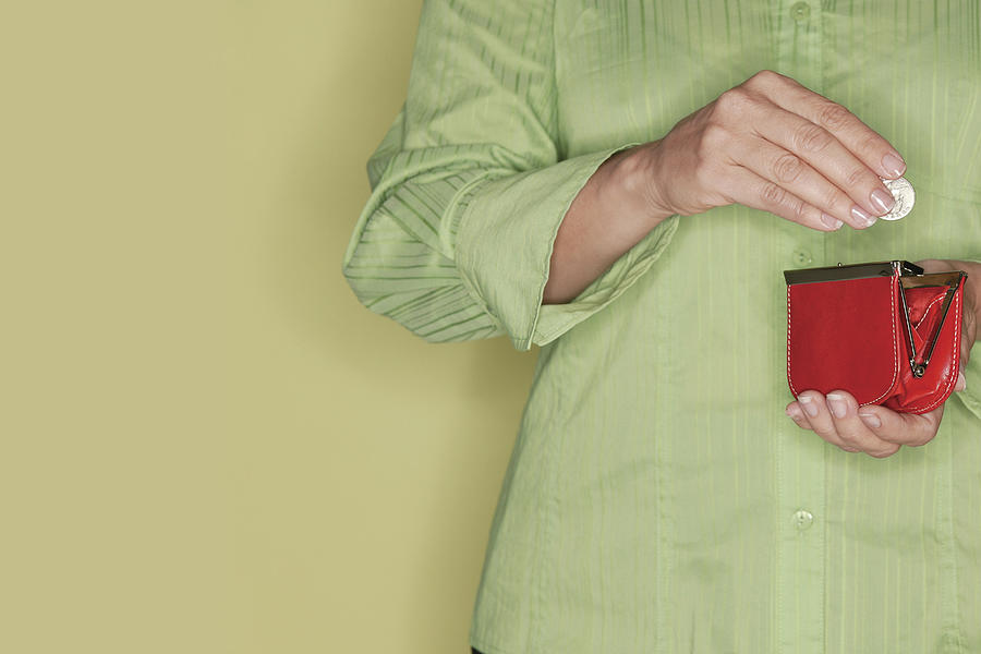 Hands of woman holding change and change purse Photograph by Comstock Images