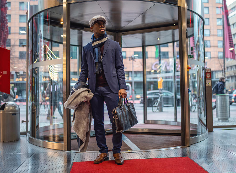 Handsome entrepreneur entering the mall through a revolving door Photograph by FluxFactory